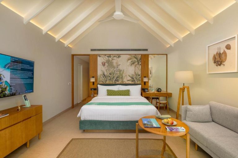 Habitación de una Beach Villa en RAAYA by Atmosphere, Maldivas, con diseño tropical elegante, cama king size y ambiente luminoso.