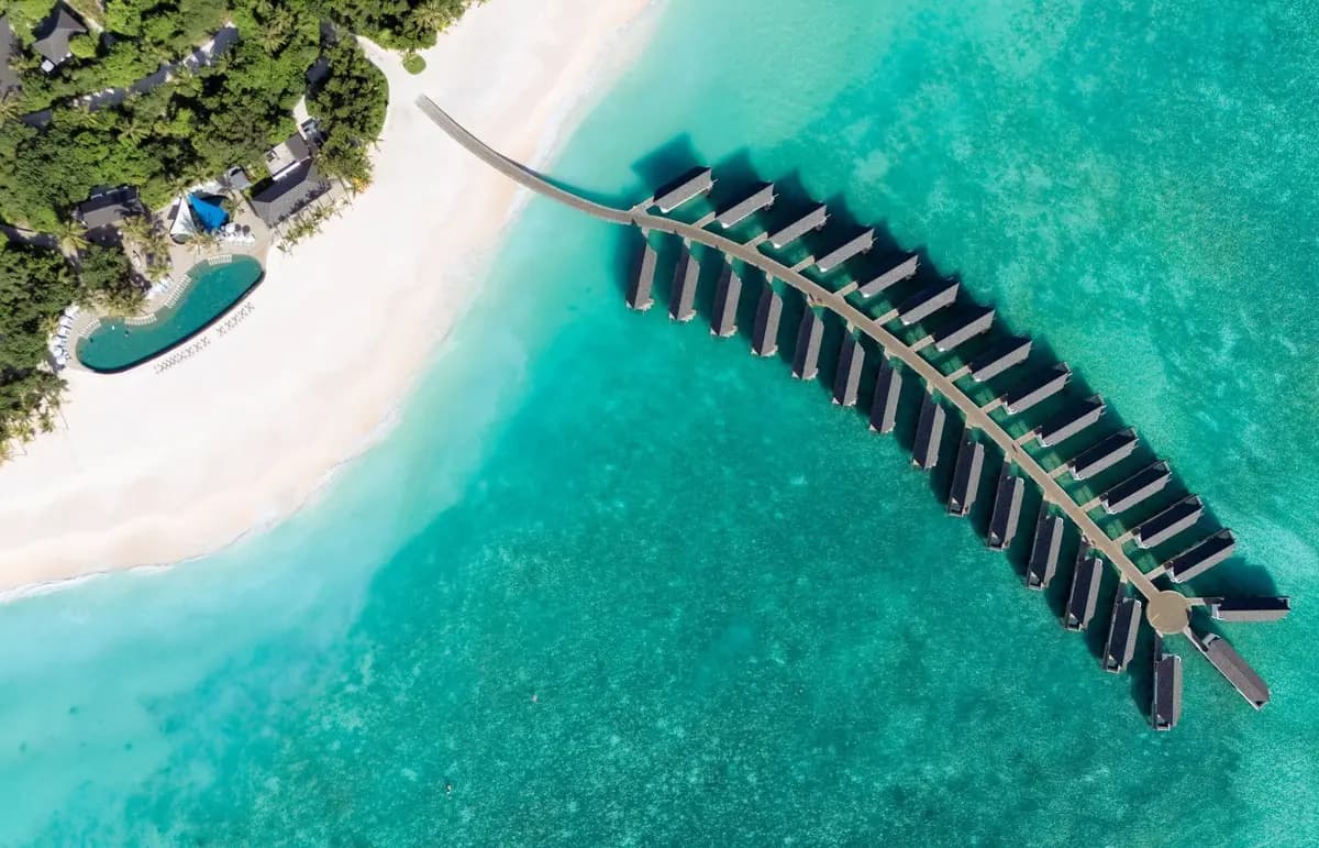 Vista aérea de RAAYA by Atmosphere en Maldivas, resort de lujo rodeado de playa de arena blanca, villas sobre el agua y laguna turquesa en Raa Atoll.