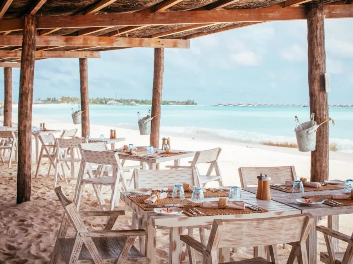 Restaurante frente al mar en Finolhu Baa Atoll, Maldivas, con mesas junto a la playa y vistas a la laguna turquesa